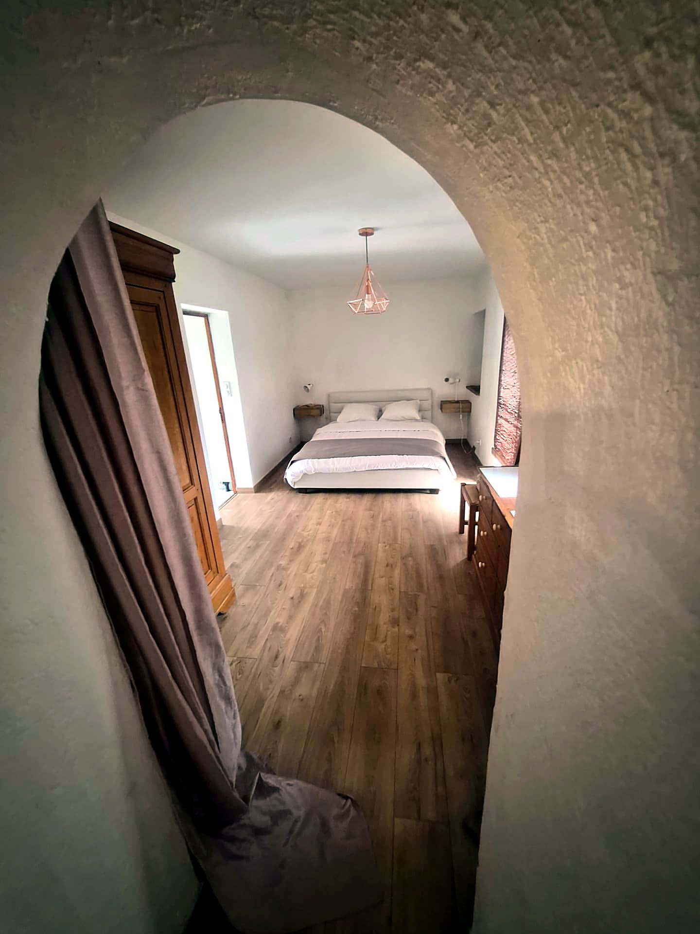 Ground-floor double bedroom through a stone archway and ensuite bathroom