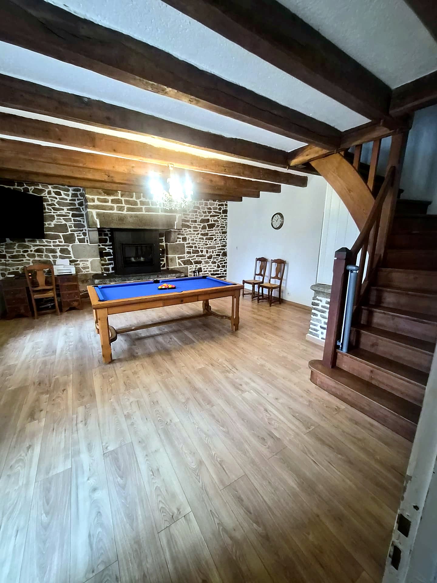 Billiards table beside the stone fireplace and staircase